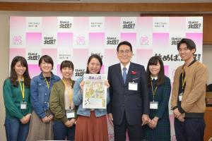 写真：完成した広報紙の特集号を持つメンバーと花川與惣太北区長（中央）