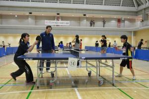 宮﨑義仁氏に指導を受けながら日本大学の卓球部員とラリーをする児童