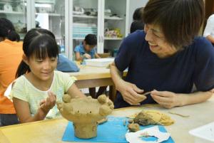 写真：苺飾りをつけた縄文土器を制作する親子