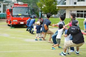 写真：消防車と綱引きをする参加者の様子
