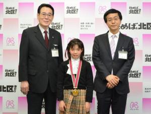 写真：受賞した糸山さくらさんと花川区長（左）・清正教育長（右）
